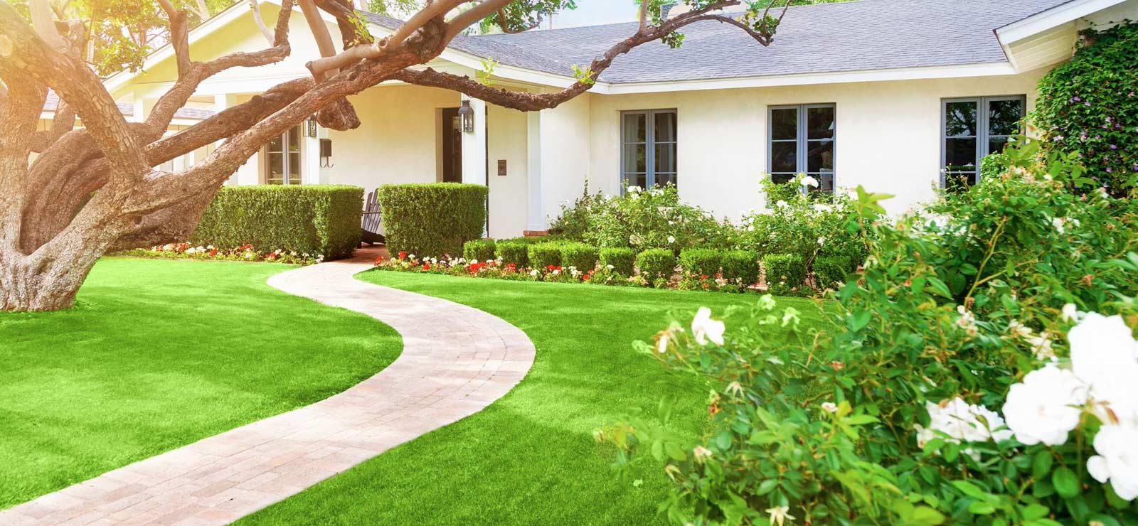 A picture of a house with a nice lawn and garden with walking path
